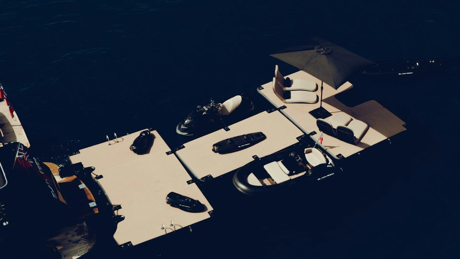 a group of people sitting around a table with umbrellas on it aboard BLACK ROCK Yacht for Sale