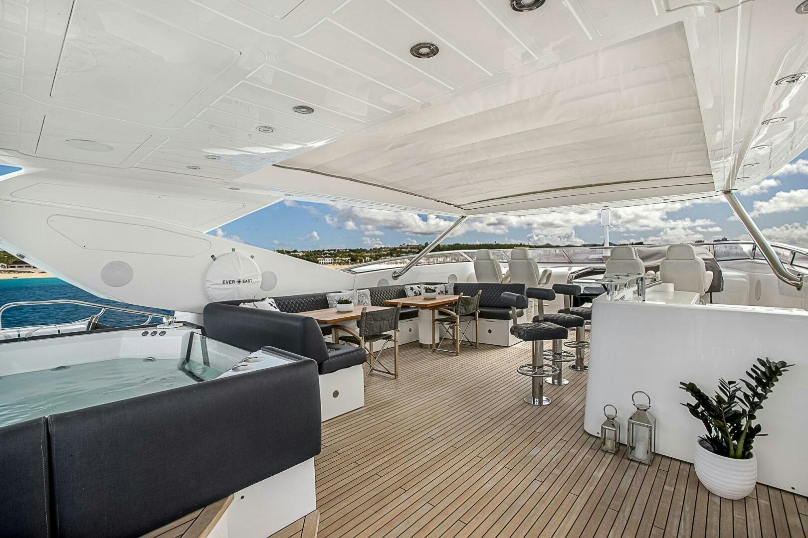 a room with a pool and a deck with chairs and tables aboard EVEREAST Yacht for Sale