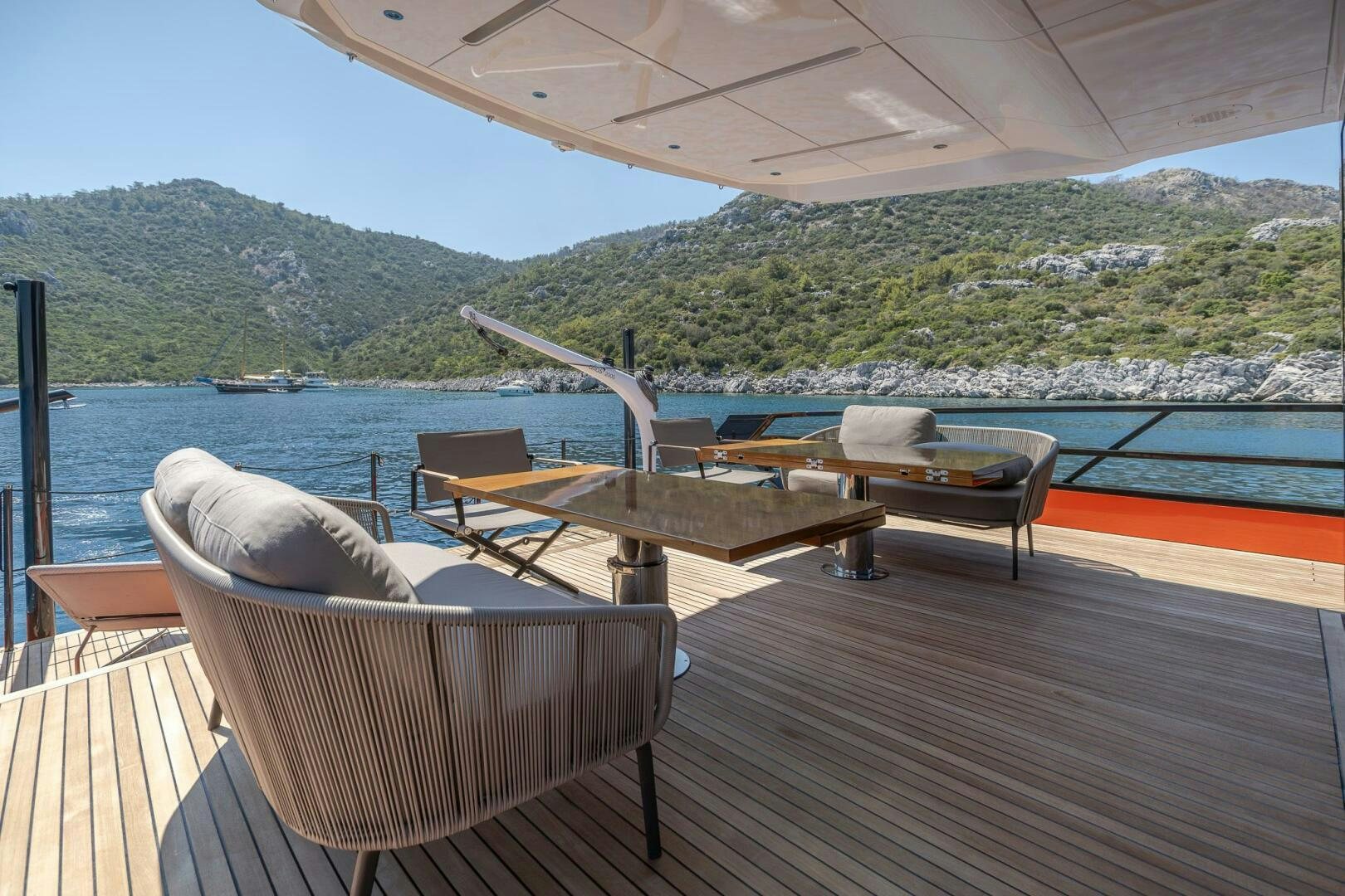 a deck with chairs and tables on it by a body of water aboard EDGE Yacht for Sale
