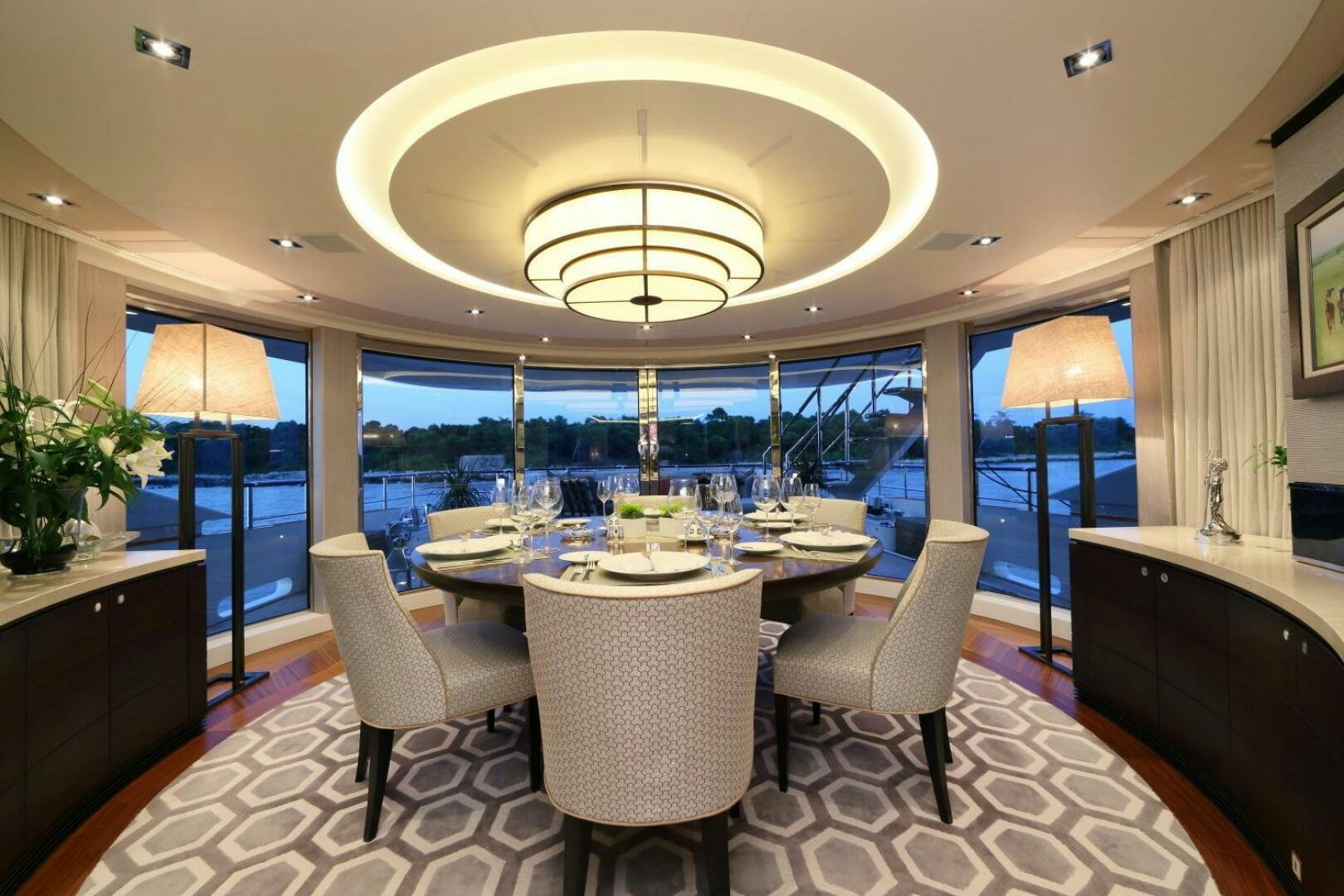 a room with a table chairs and a chandelier aboard AURELIA Yacht for Sale
