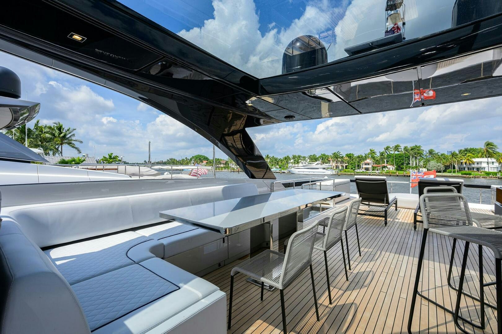 a deck with a deck chairs and a large building with trees and blue sky aboard RISE ABOVE III Yacht for Sale