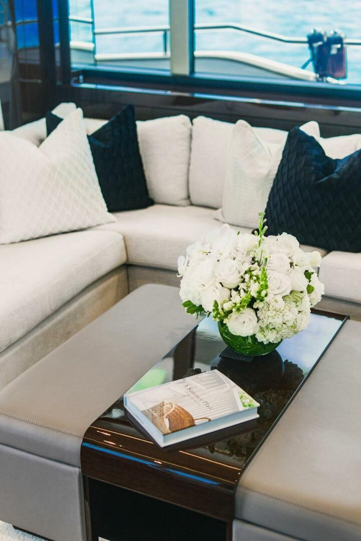 a white couch with pillows and flowers aboard PURA VIDA Yacht for Sale
