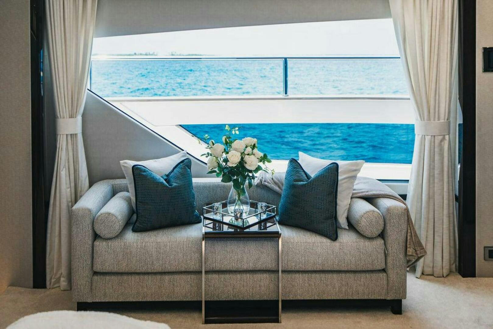 a living room with a large blue ocean aboard PURA VIDA Yacht for Sale