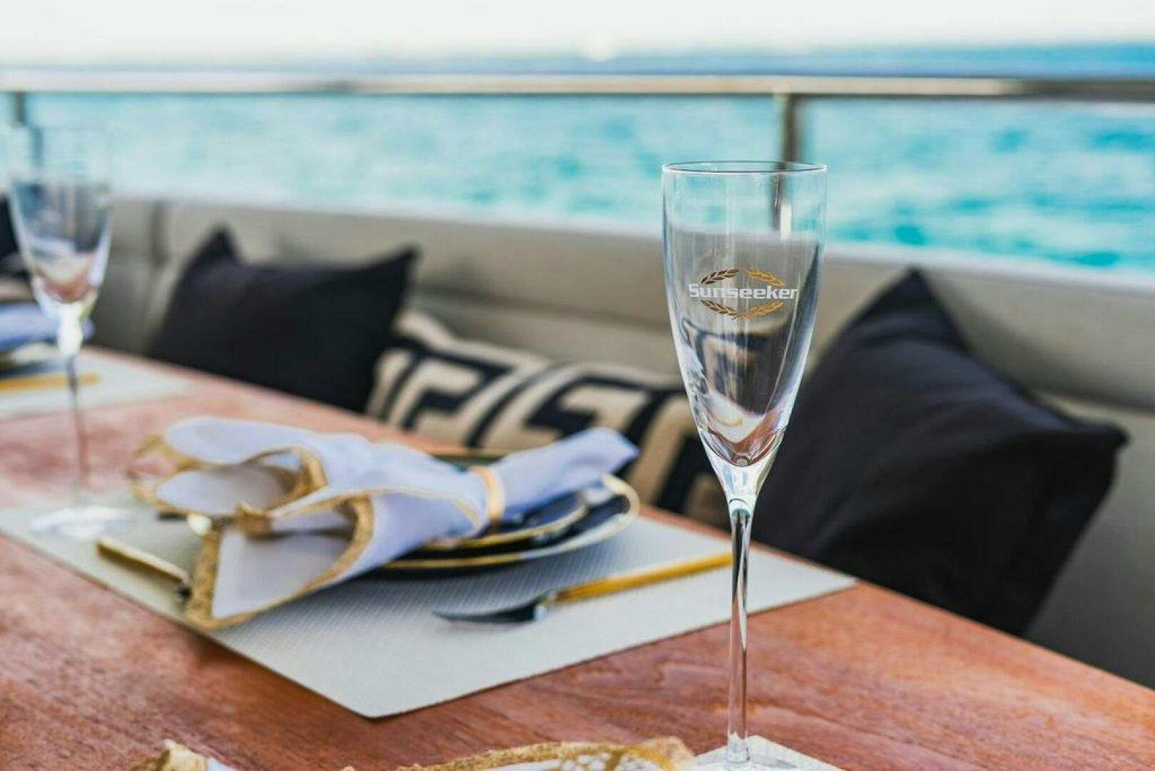 a table with a plate of food and a glass of wine aboard PURA VIDA Yacht for Sale