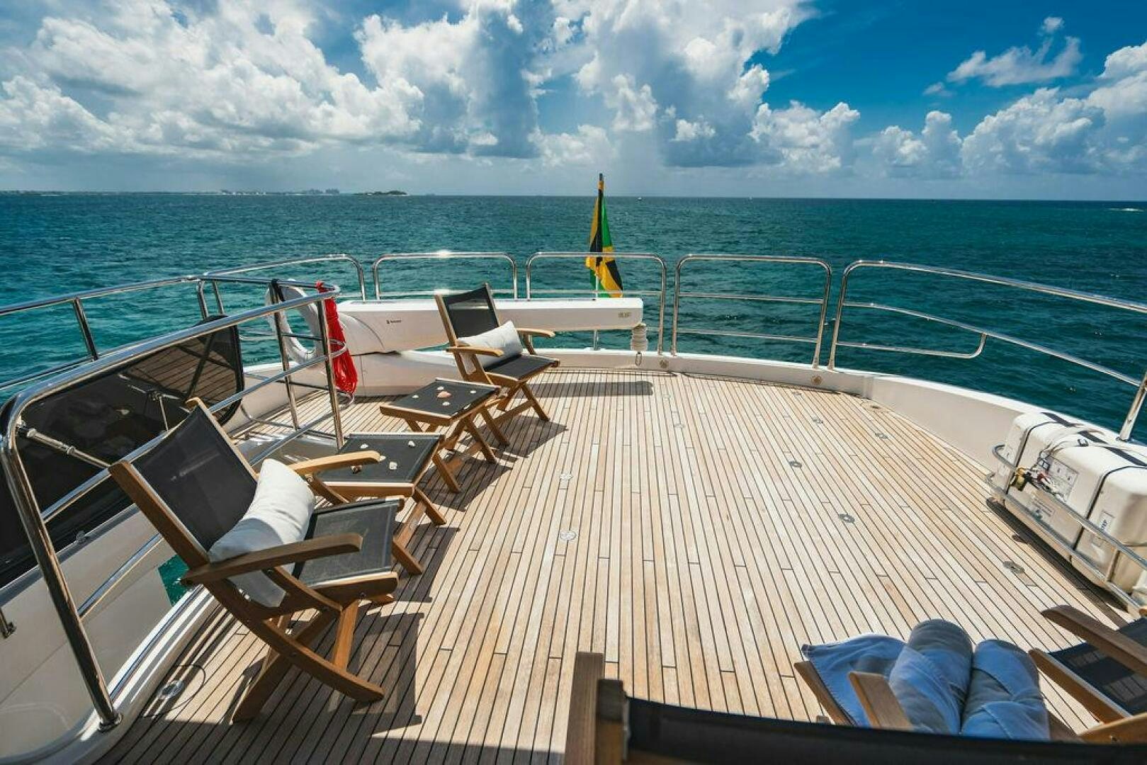 a deck with chairs and a body of water in the background aboard PURA VIDA Yacht for Sale