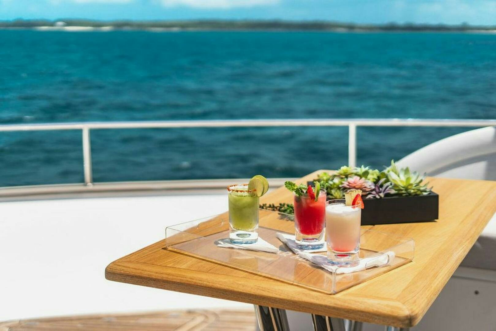 a table with drinks on it by the ocean aboard PURA VIDA Yacht for Sale