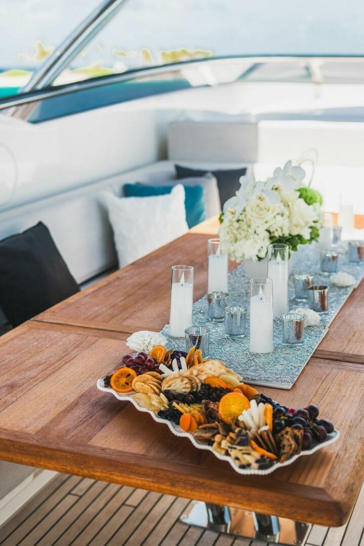 a table with a plate of food and flowers on it aboard PURA VIDA Yacht for Sale