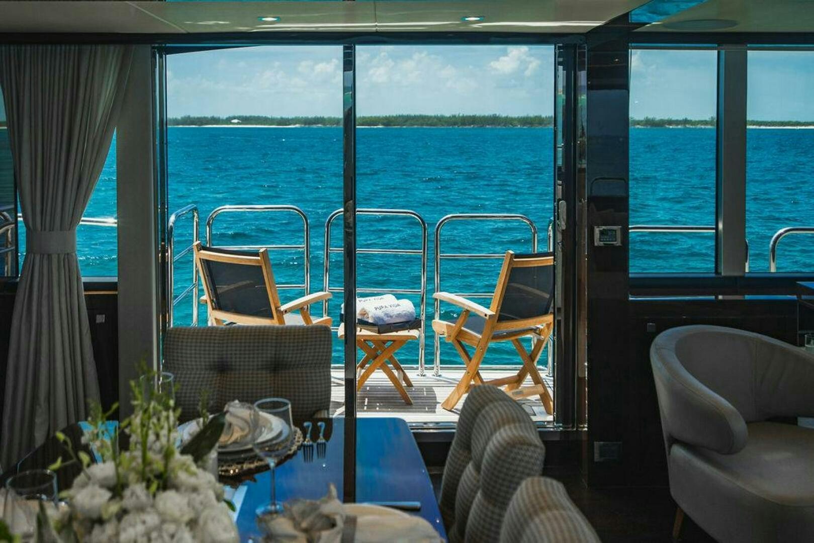 a balcony with a table and chairs aboard PURA VIDA Yacht for Sale
