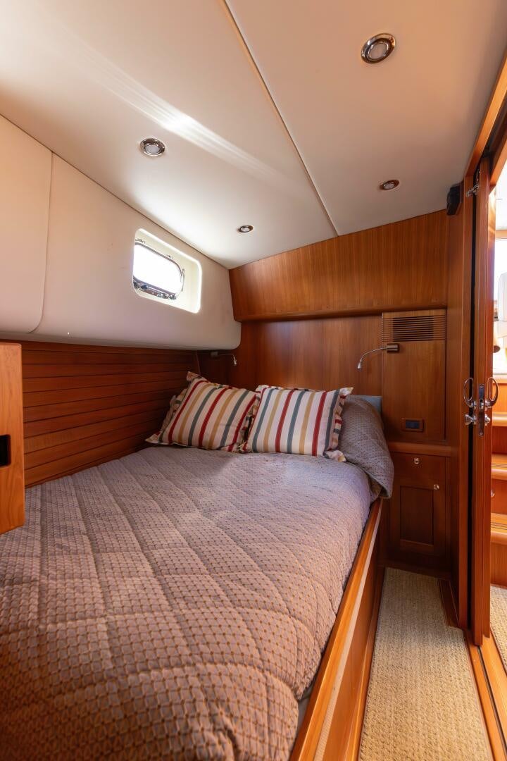 a bed with a pink and white striped pillow aboard FINALLY US Yacht for Sale