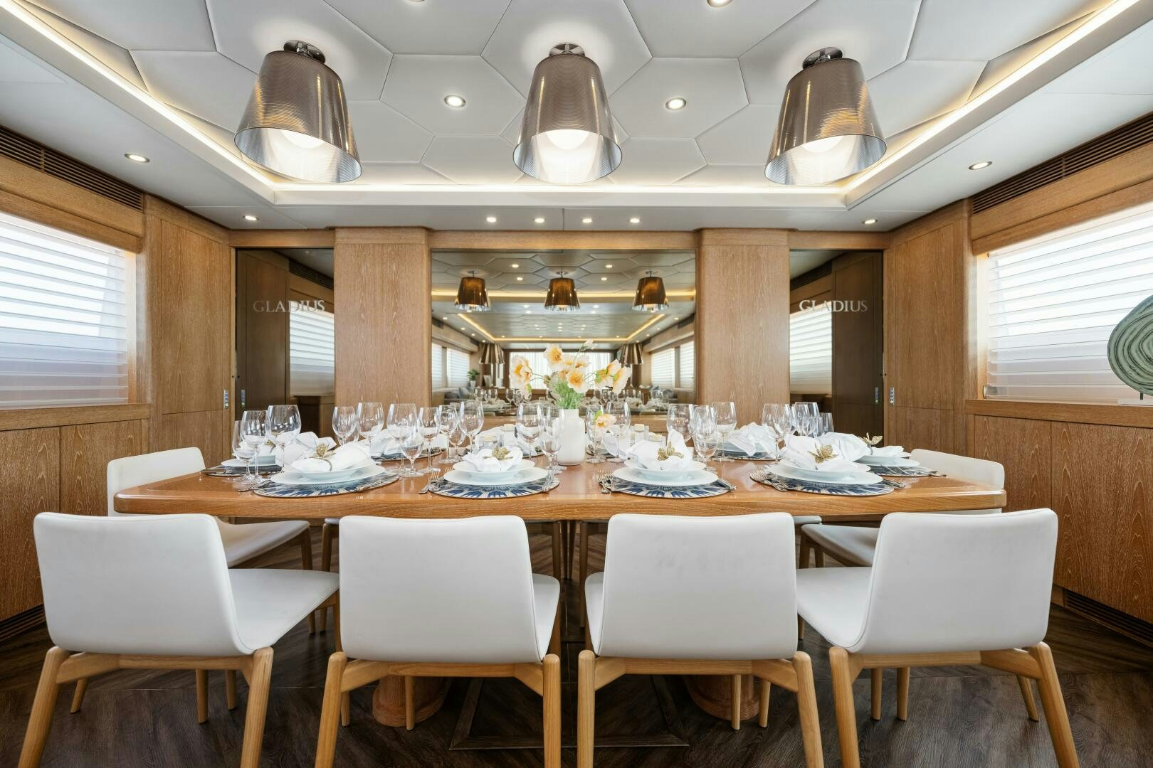 a large dining table with white chairs aboard GLADIUS Yacht for Sale