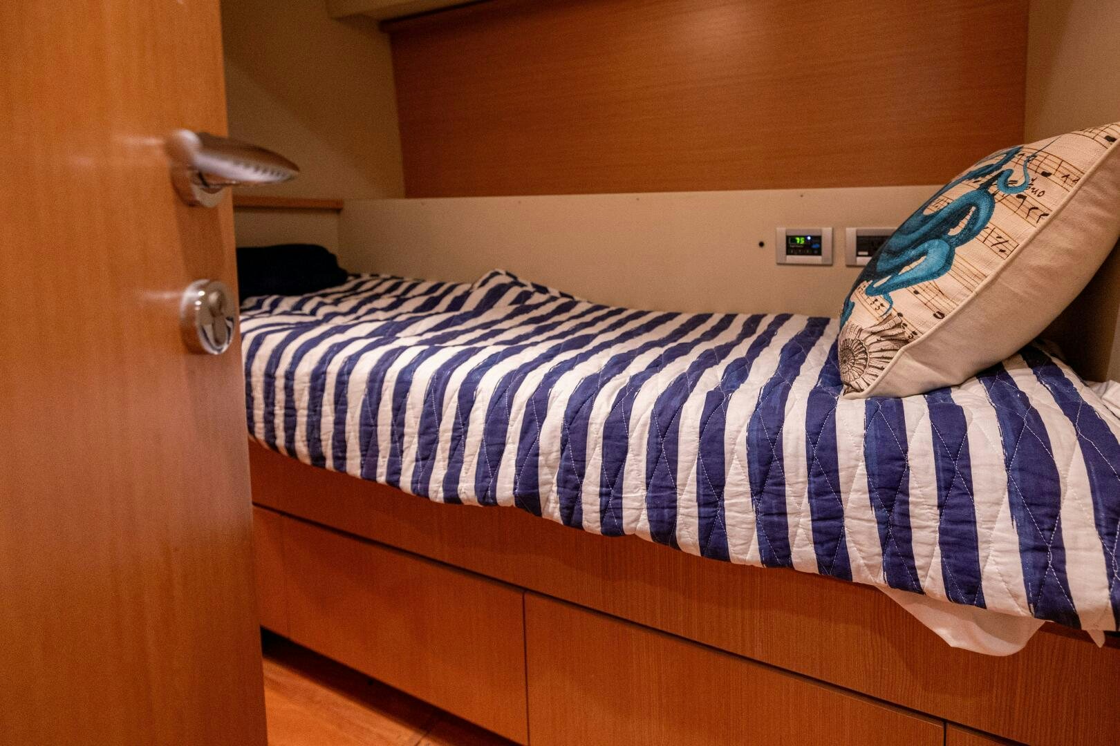 a bed with a blue and white striped blanket aboard CRYSTAL PARROT Yacht for Sale