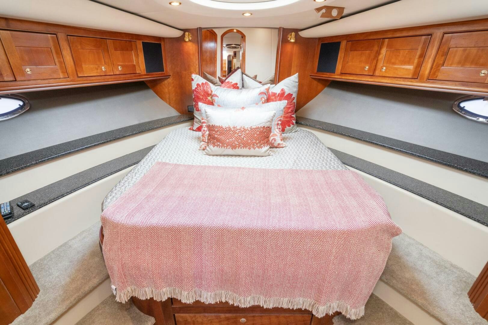 a large pink and white bed in a room with wooden cabinets aboard MYSTIQUE Yacht for Sale