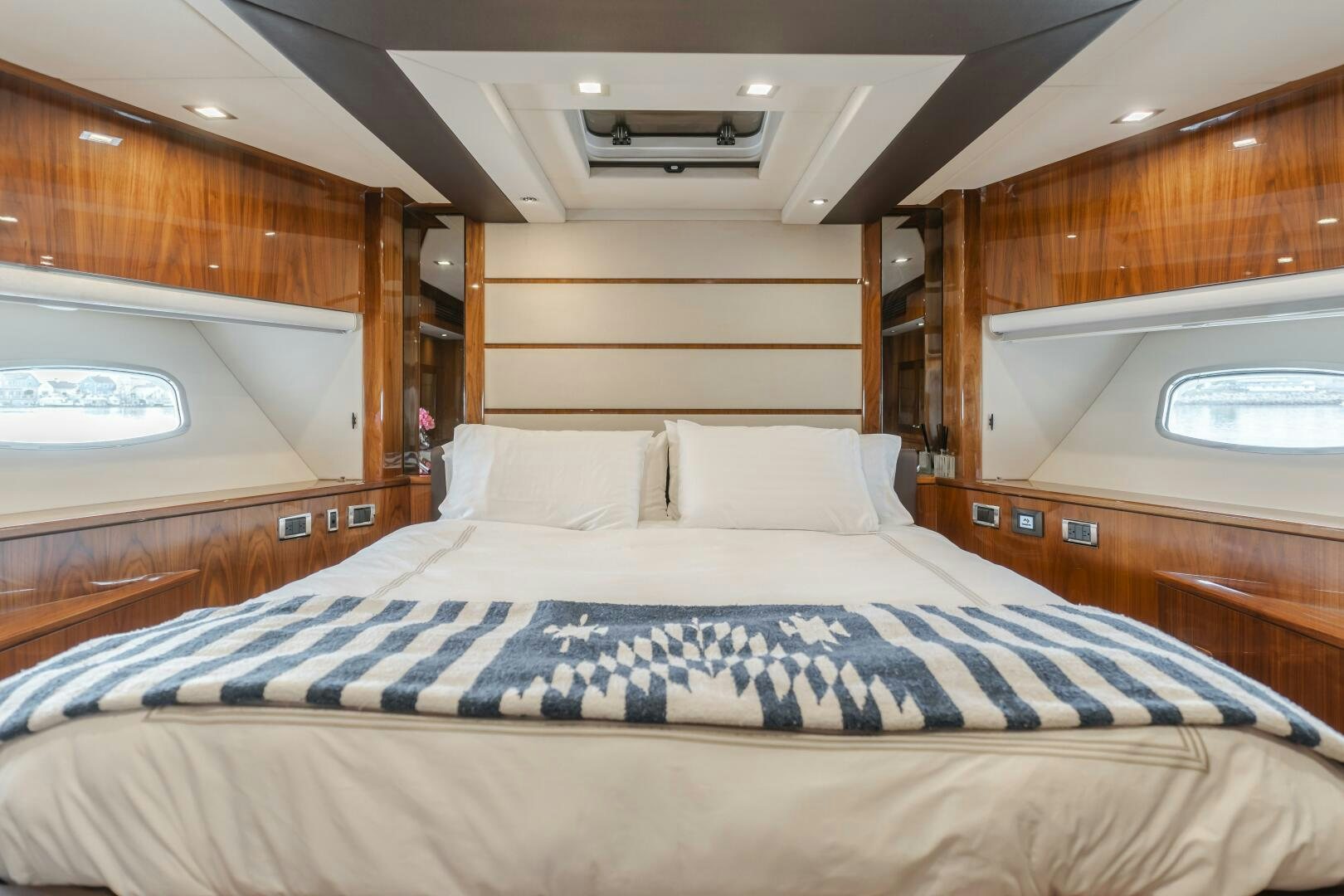 a bed with a blue and white comforter and a wooden wall aboard INDECENT PROPOSAL IV Yacht for Sale