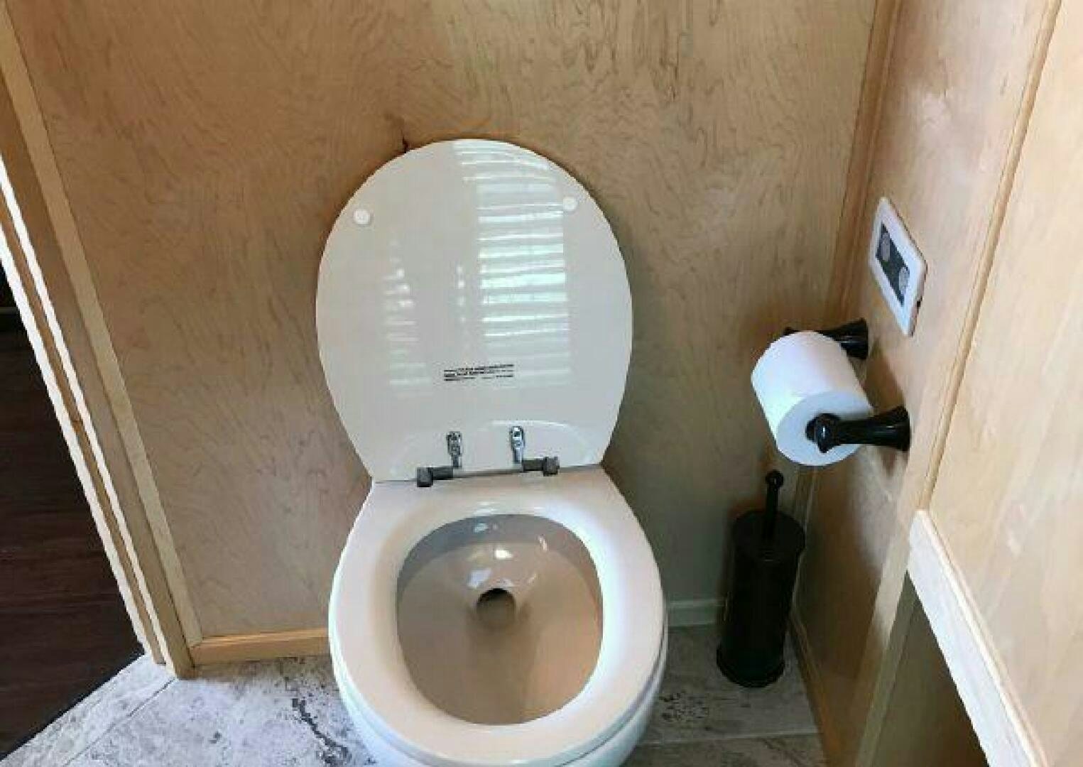 a toilet with a roll of toilet paper on the tank aboard ST. SOMEWHERE Yacht for Sale