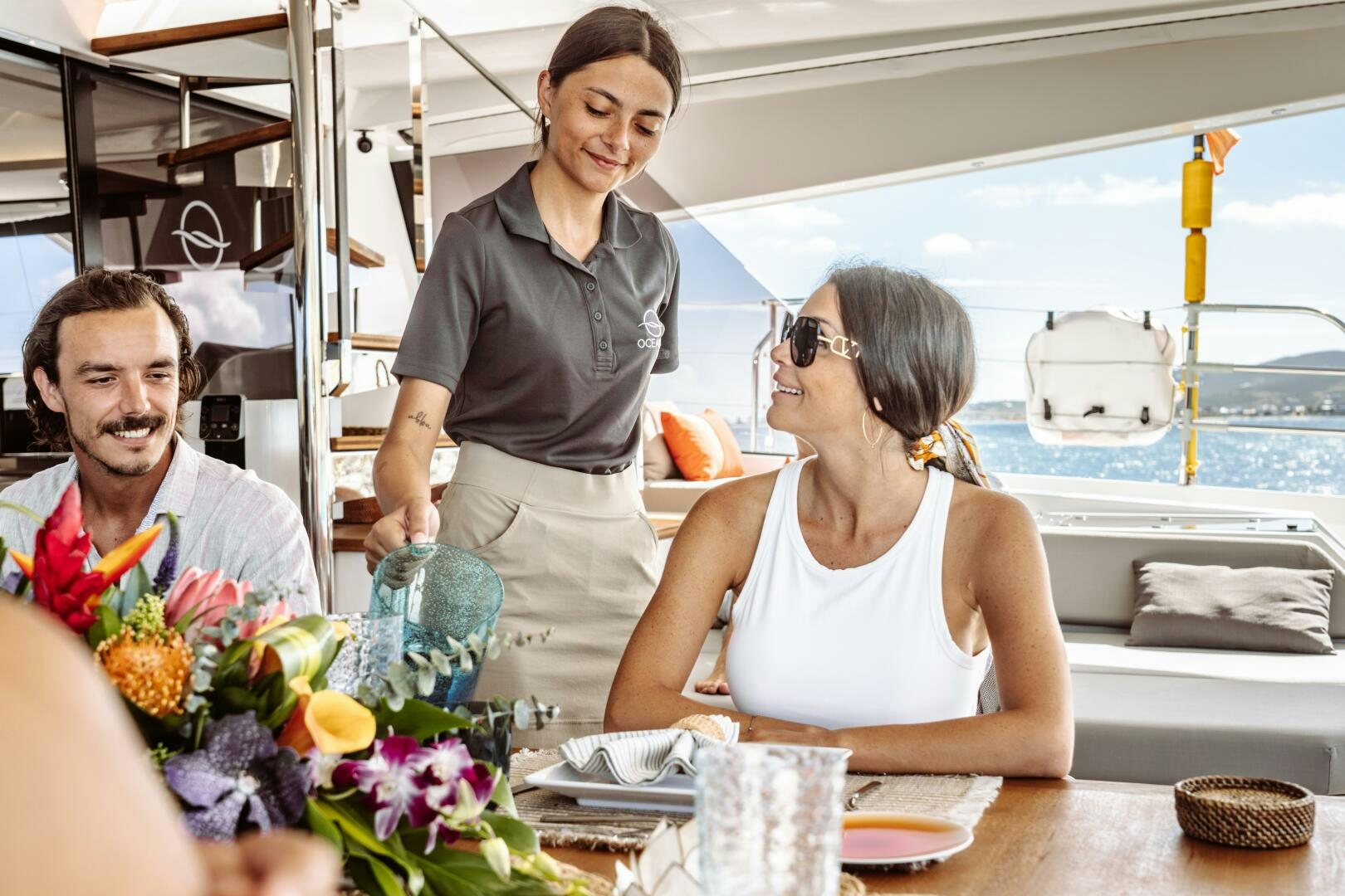 a man and a woman standing at a table with food and drinks aboard OCEANUS Yacht for Sale