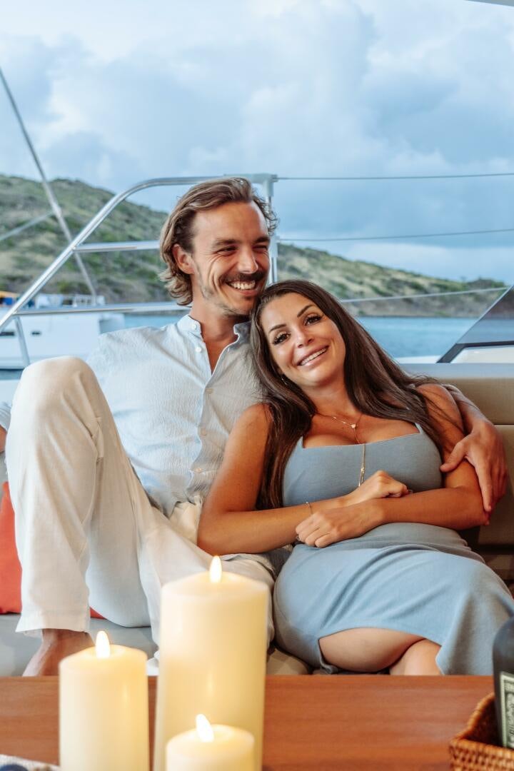 a man and woman sitting on a boat with a woman holding a candle aboard OCEANUS Yacht for Sale