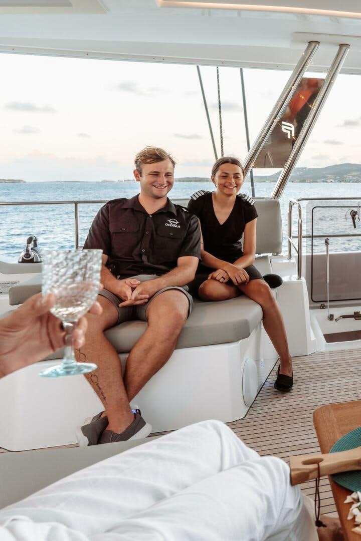 a man and woman sitting on a boat with wine glasses aboard OCEANUS Yacht for Sale