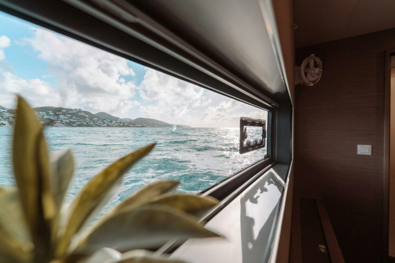 a window with a view of the ocean and the land below aboard OCEANUS Yacht for Sale