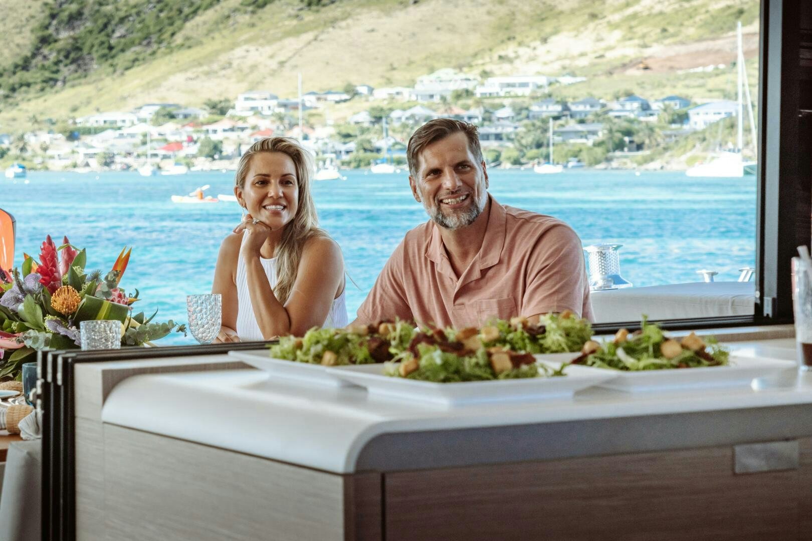 a man and woman sitting at a table with food on it aboard OCEANUS Yacht for Sale