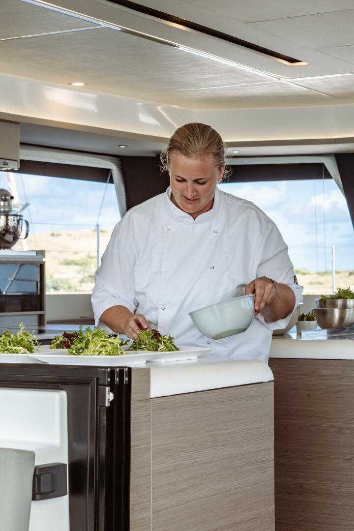 a man in a kitchen preparing a meal aboard OCEANUS Yacht for Sale