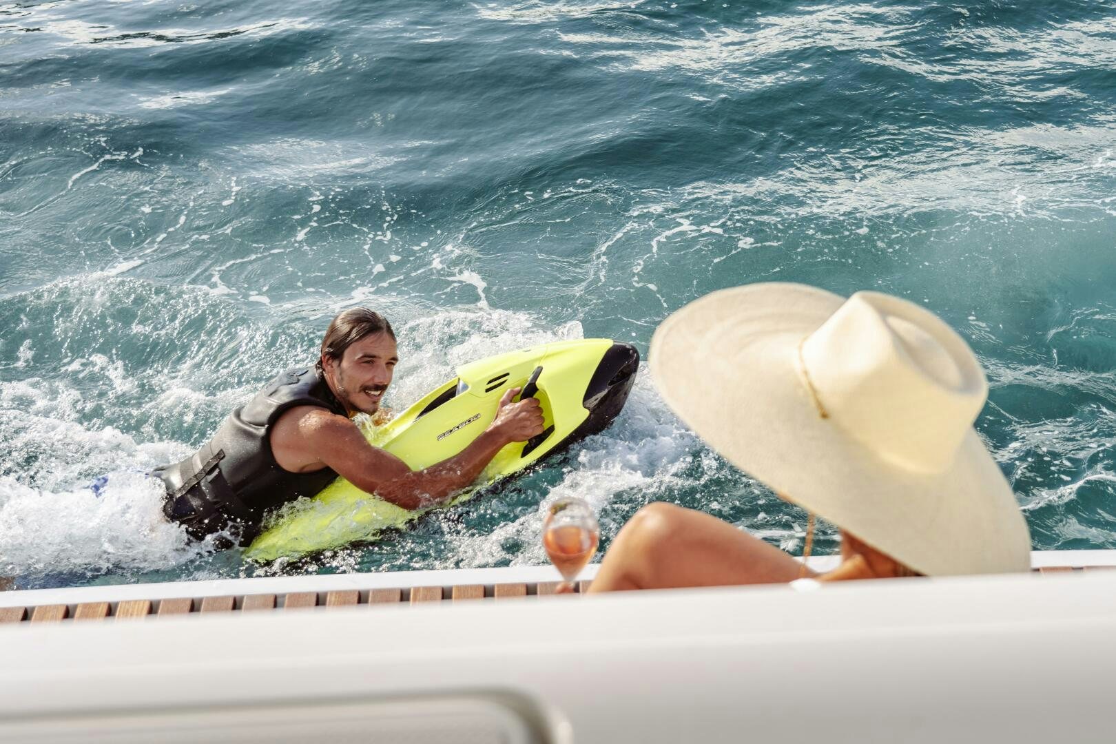 a person lying on a surfboard in the water aboard OCEANUS Yacht for Sale