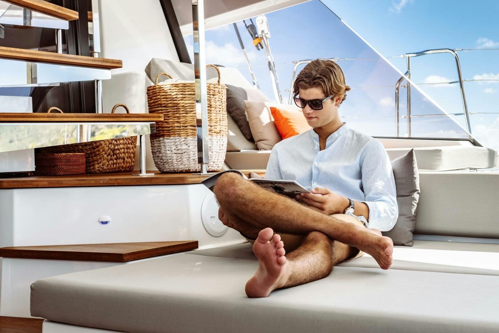 a man sitting on a couch reading a book aboard OCEANUS Yacht for Sale