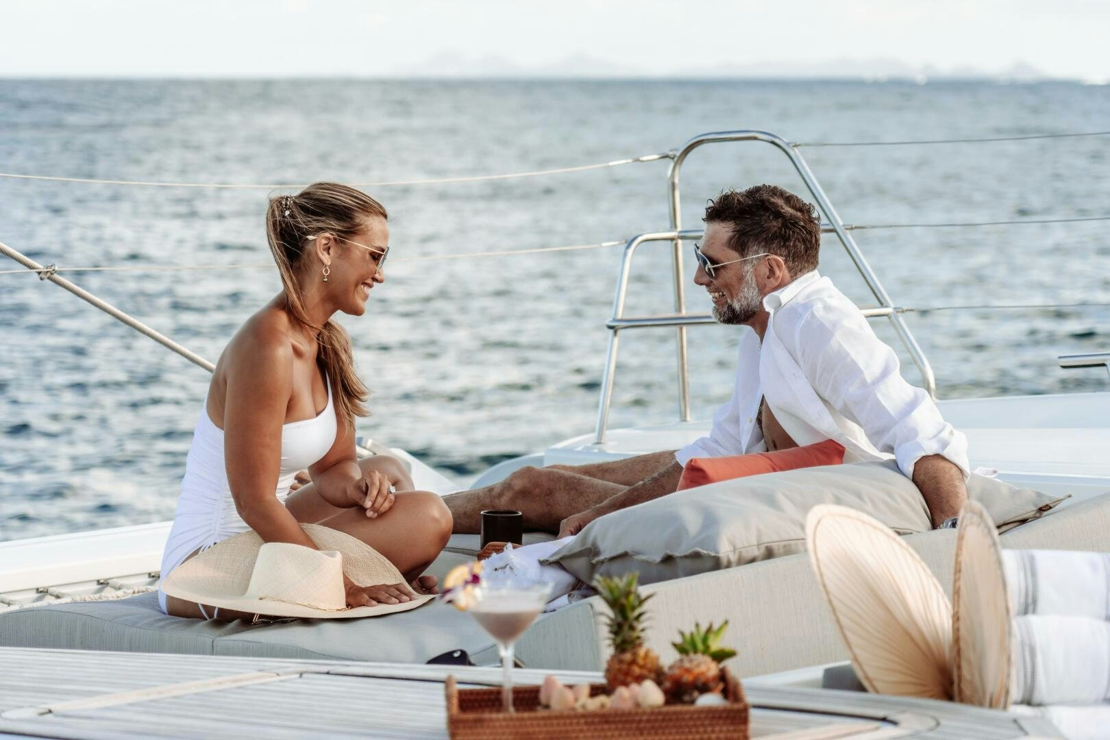 a man and woman sitting on a boat with a drink and looking at each other aboard OCEANUS Yacht for Sale