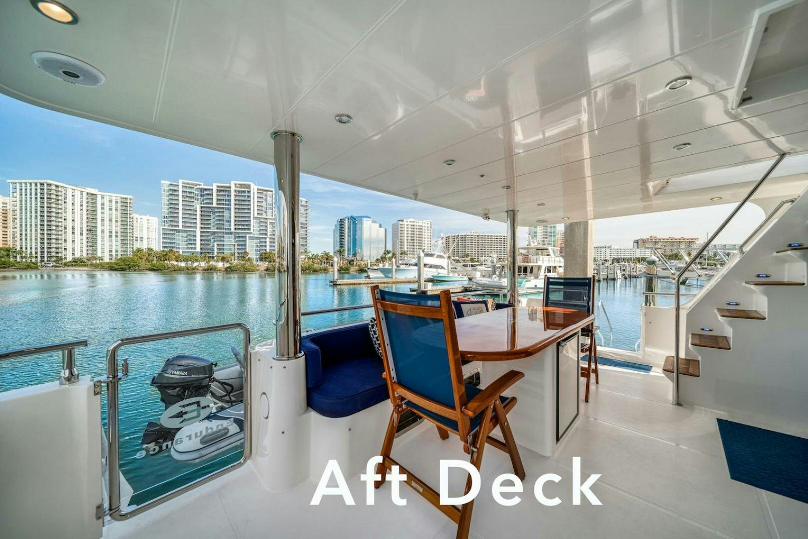 a room with a table and chairs on a deck with a view of a city aboard ESCAPE Yacht for Sale