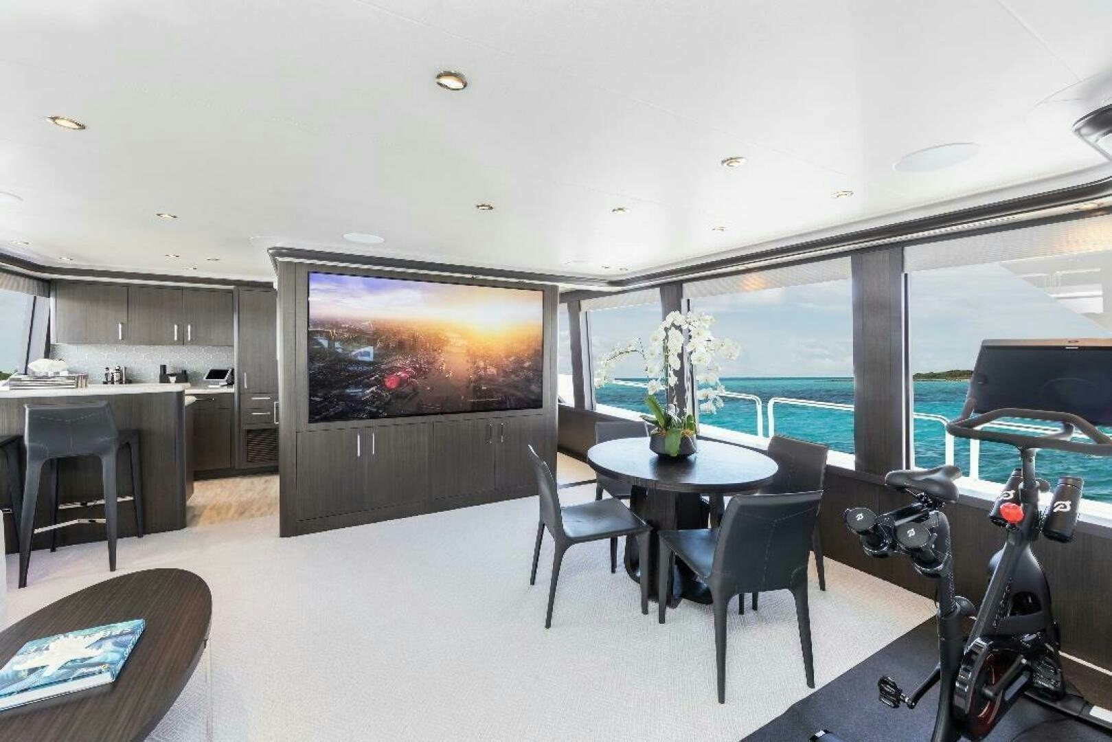 a room with a large screen and a table and chairs aboard MEMENTO VIVERE Yacht for Sale