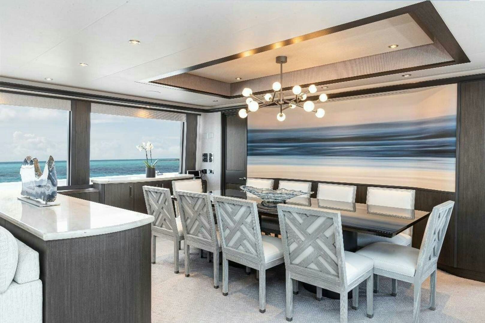 a room with a table chairs and a chandelier aboard MEMENTO VIVERE Yacht for Sale