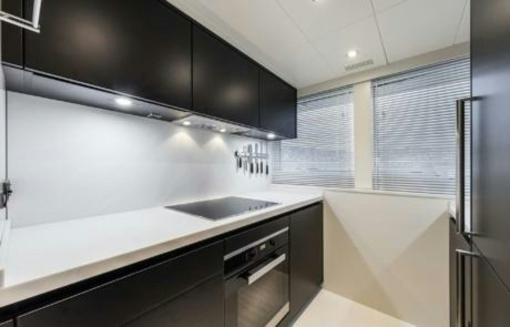 a kitchen with black cabinets aboard OCEANIC 76' GT Yacht for Sale