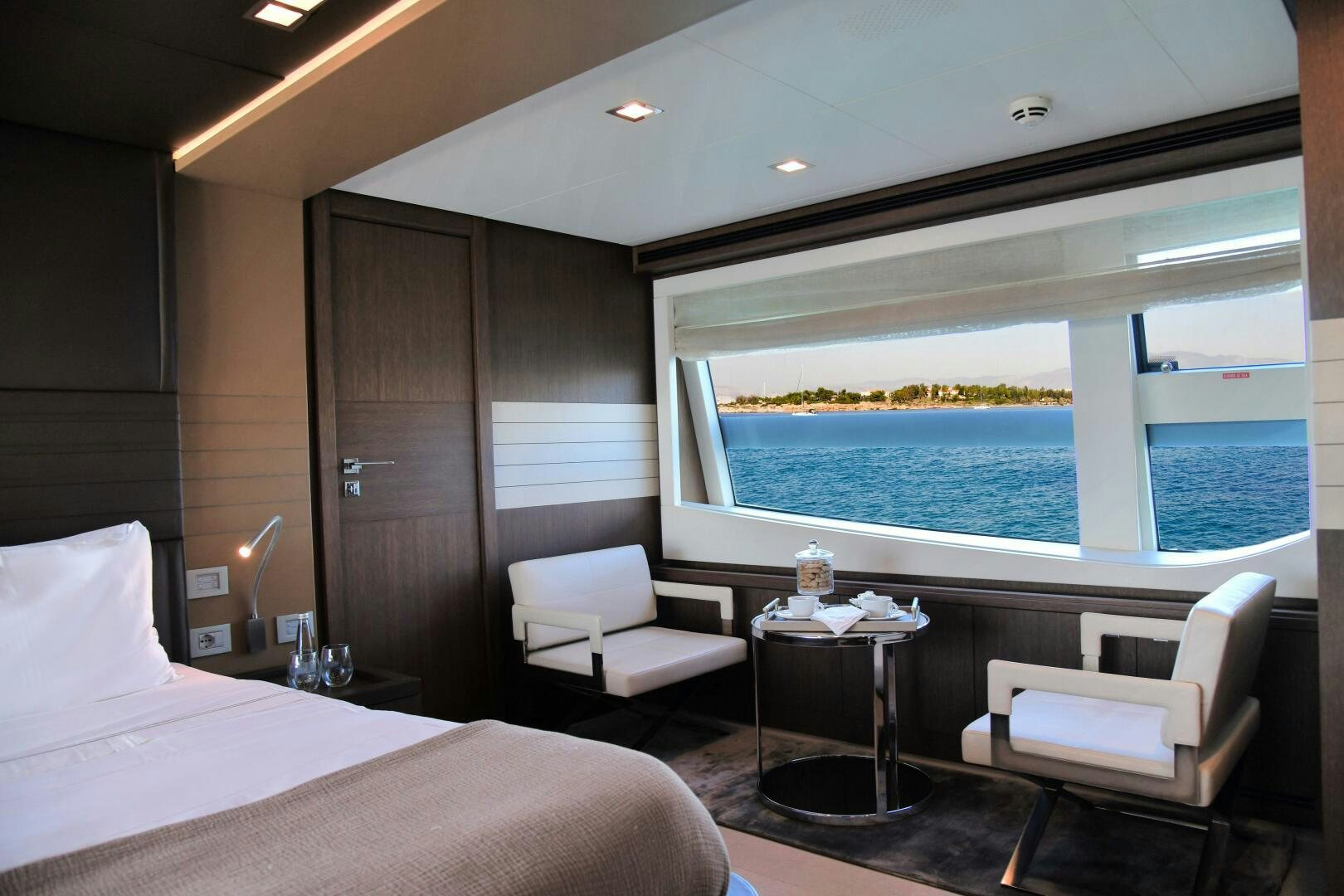 a room with a bed and a table and a chair aboard INFINITAS Yacht for Sale