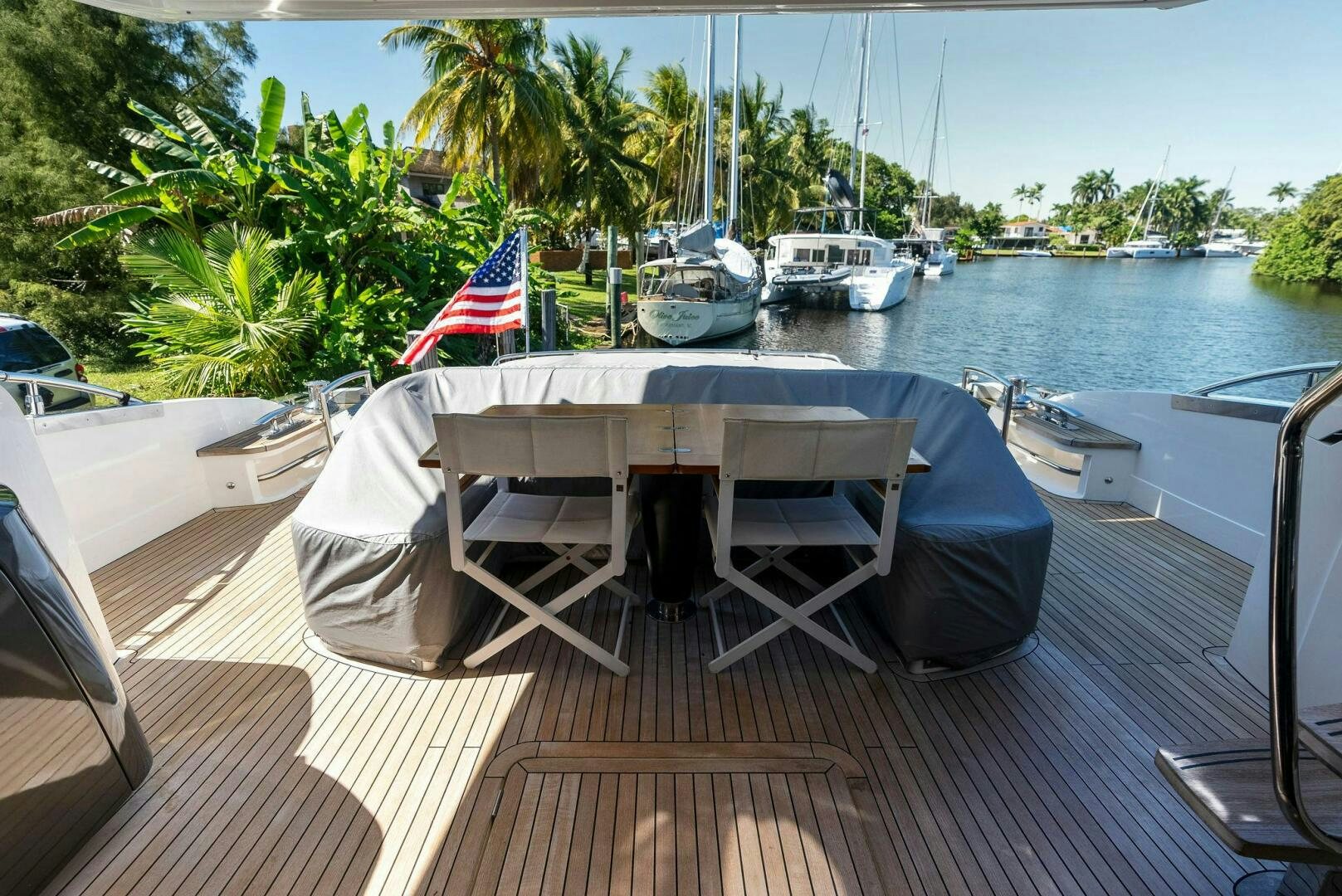 a deck with chairs and a flag on it by a body of water aboard WOODY Yacht for Sale
