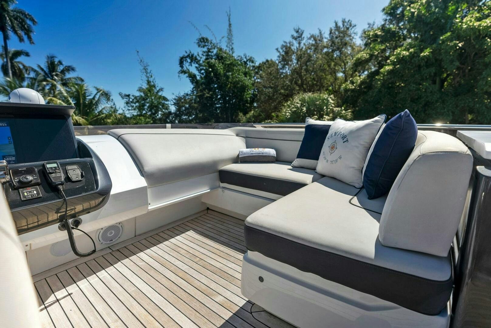 a white couch with a blue pillow on it and a white sofa on a deck with trees and aboard WOODY Yacht for Sale