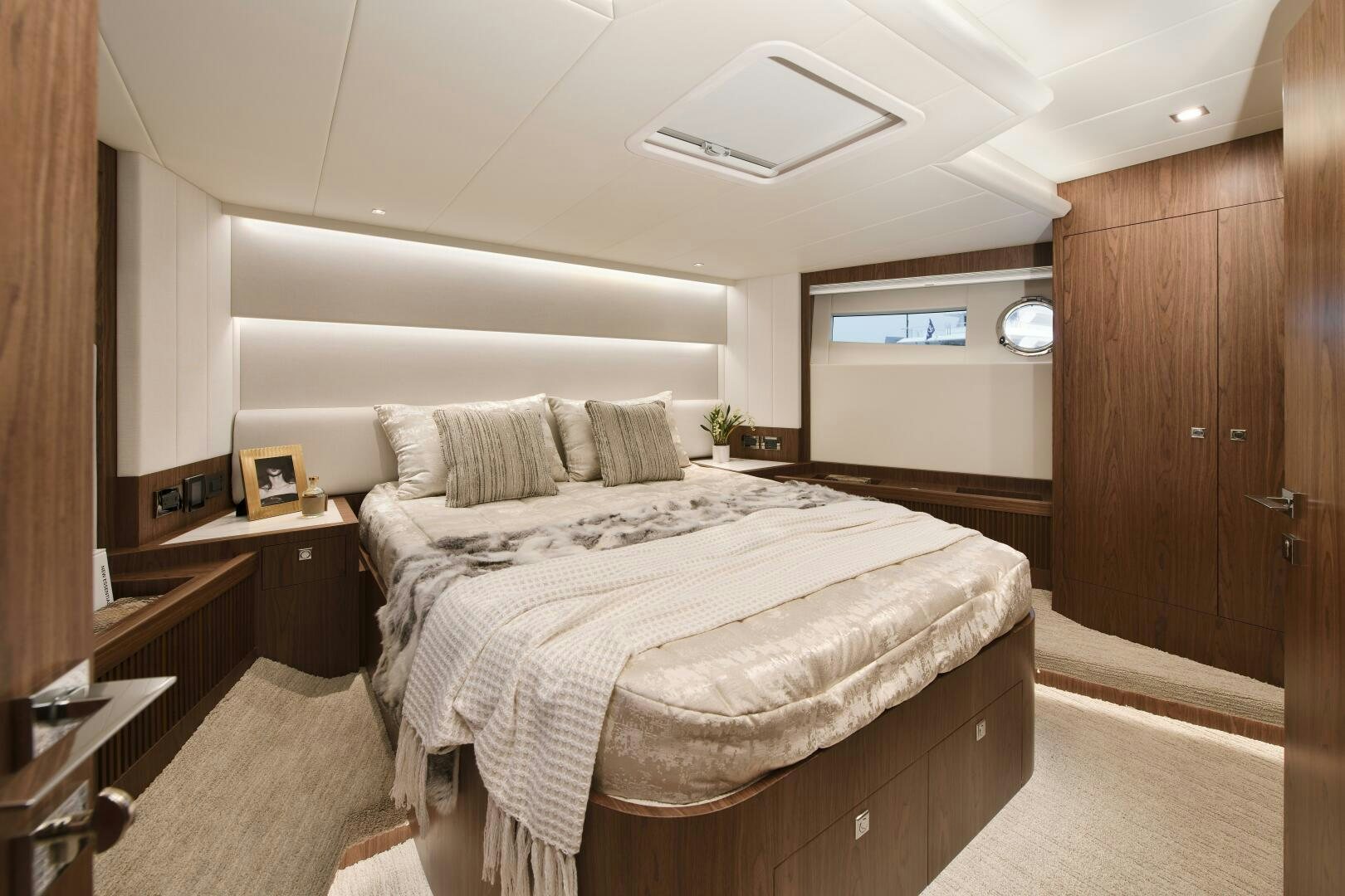 a bedroom with a bed and a wood cabinet aboard V77S 610 Yacht for Sale