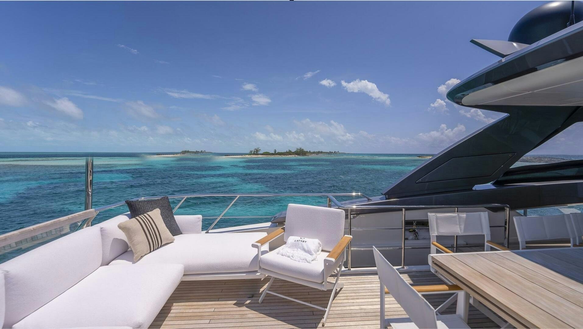 a deck with chairs and a body of water in the background aboard GATSBY Yacht for Sale