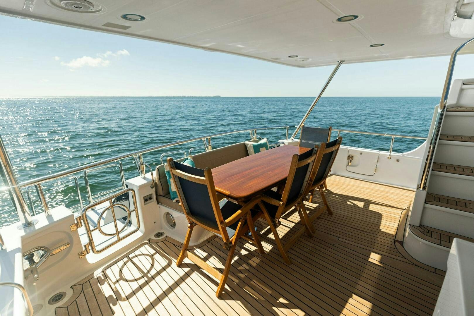 a deck with a table and chairs on it aboard SUNZSET Yacht for Sale
