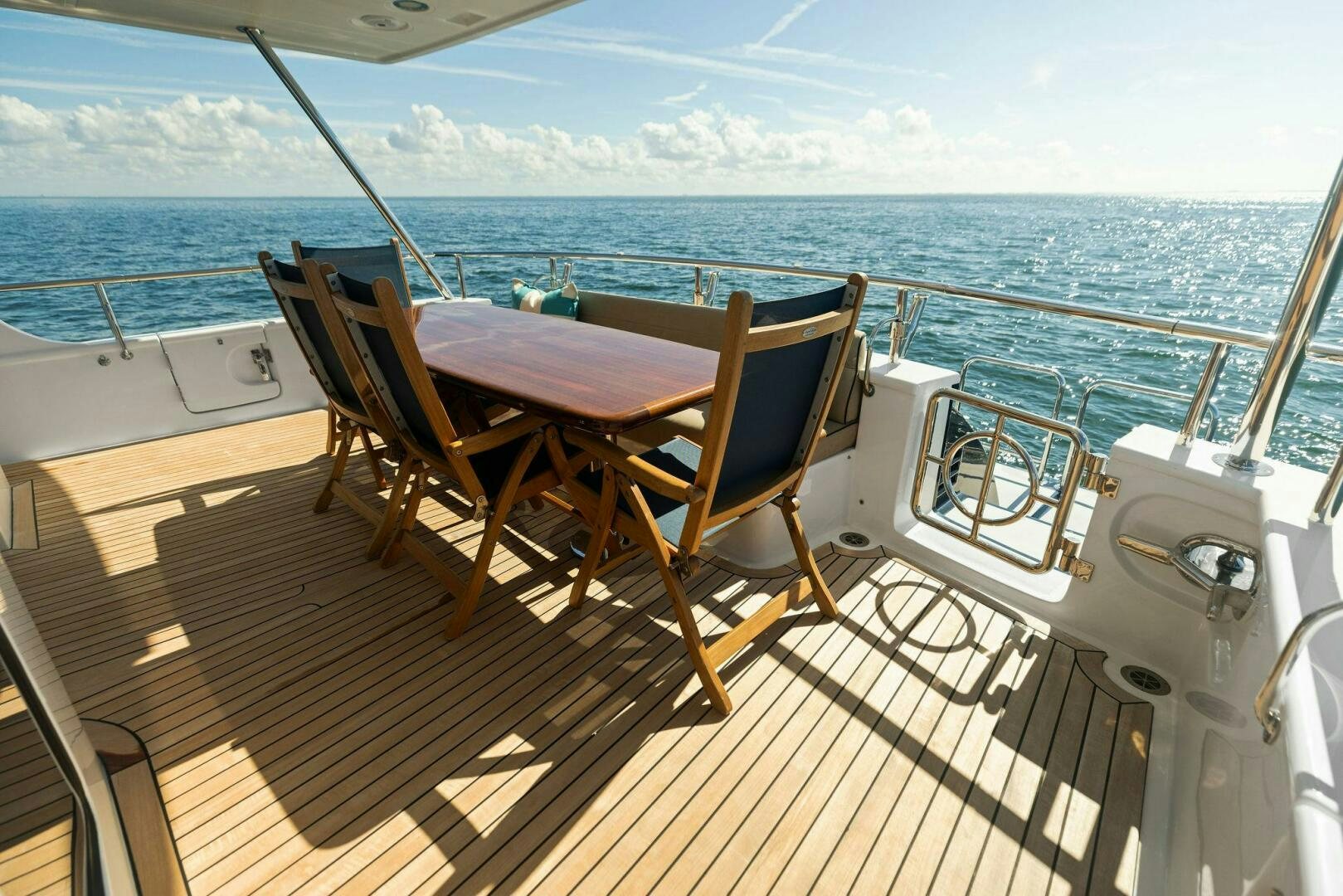 a deck with a table and chairs on it aboard SUNZSET Yacht for Sale