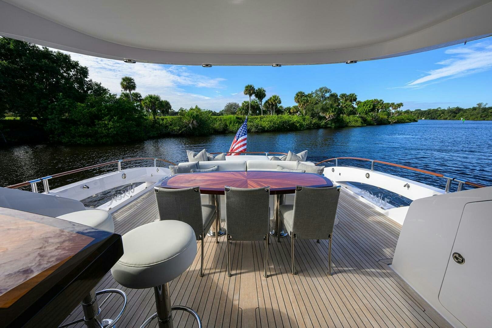a deck with a table and chairs on it by a body of water aboard VIXEN Yacht for Sale