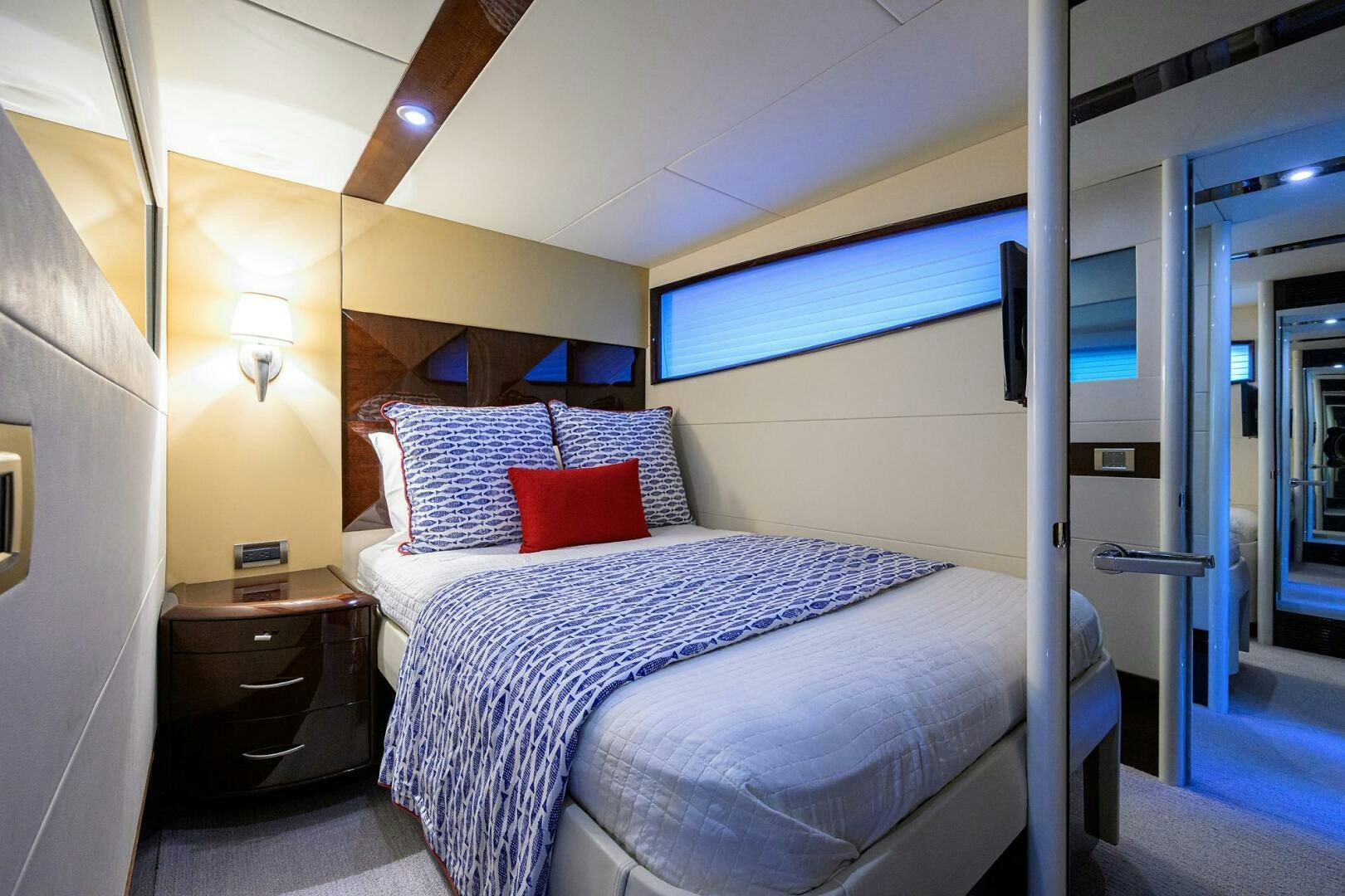 a bed with a blue and white striped pillow and a red pillow aboard VIXEN Yacht for Sale