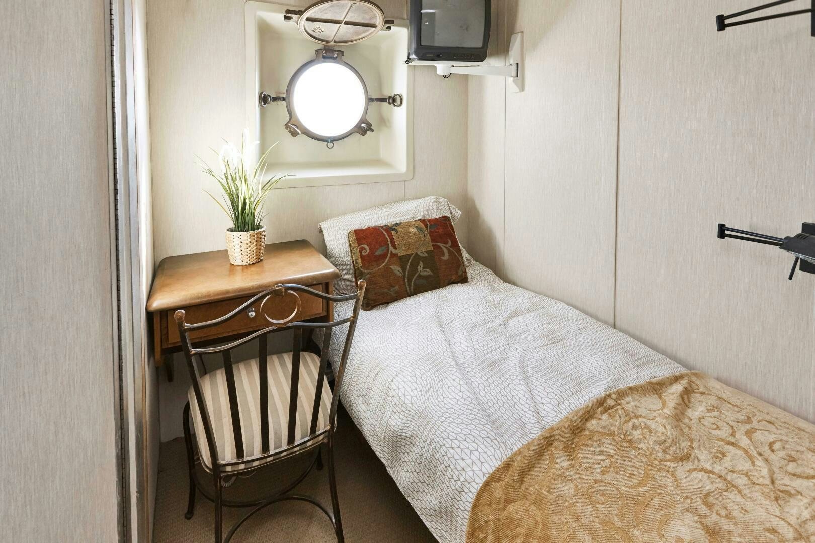 a small bed with a chair aboard SALTY Yacht for Sale