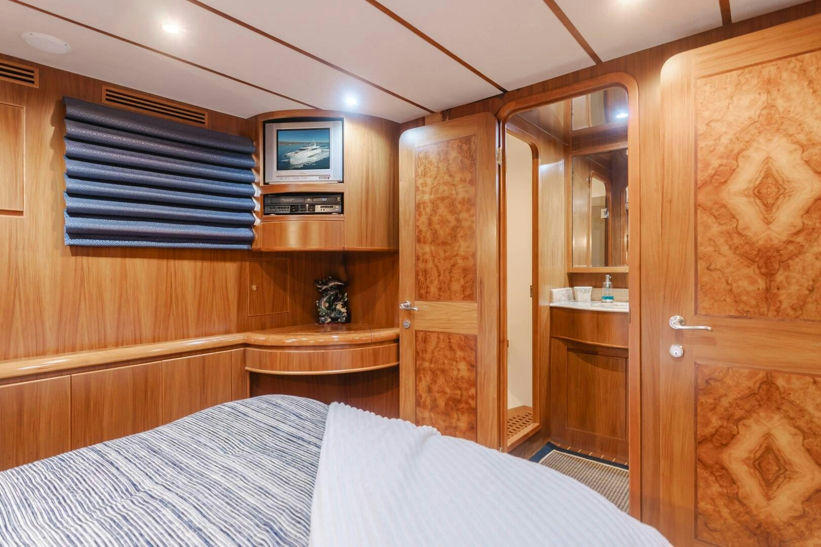 a bedroom with a bed and a wood cabinet aboard MONEY CAT Yacht for Sale