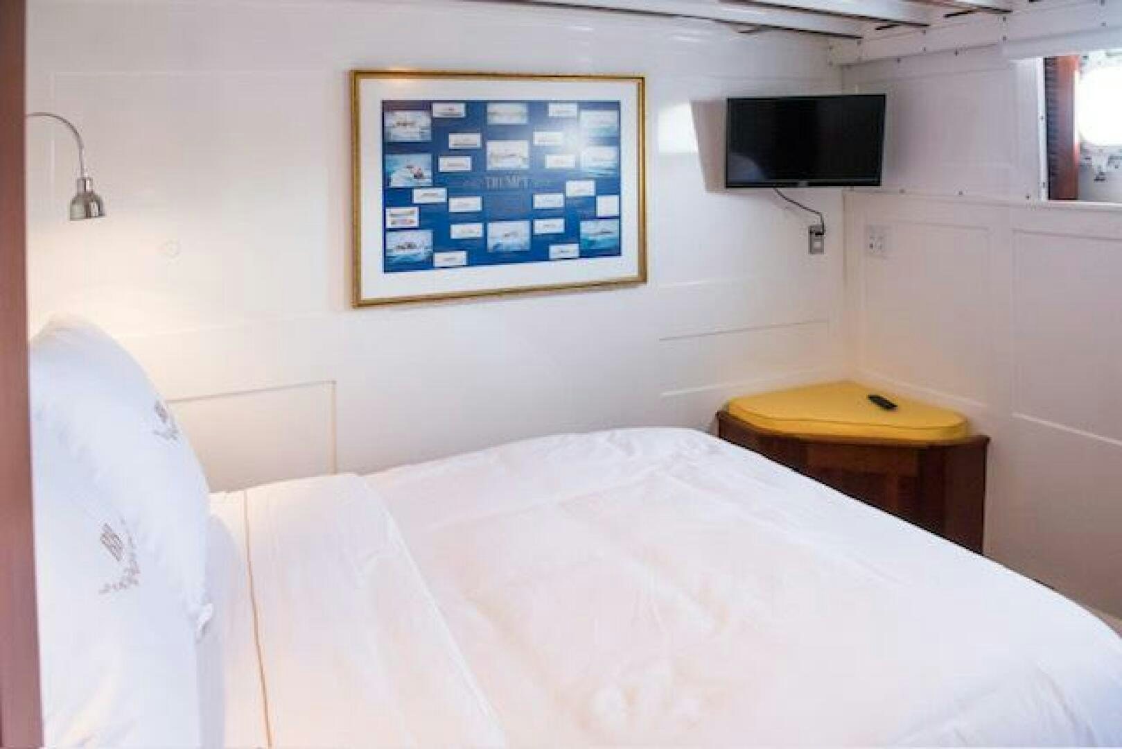 a bed with a desk and tv on the wall aboard TIMELESS Yacht for Sale