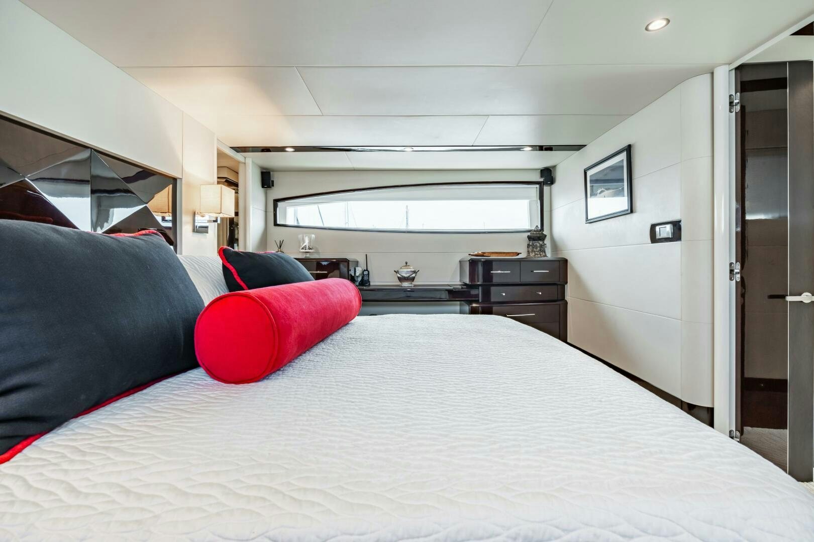 a bed with a white sheet and red pillows aboard COMMITTED Yacht for Sale