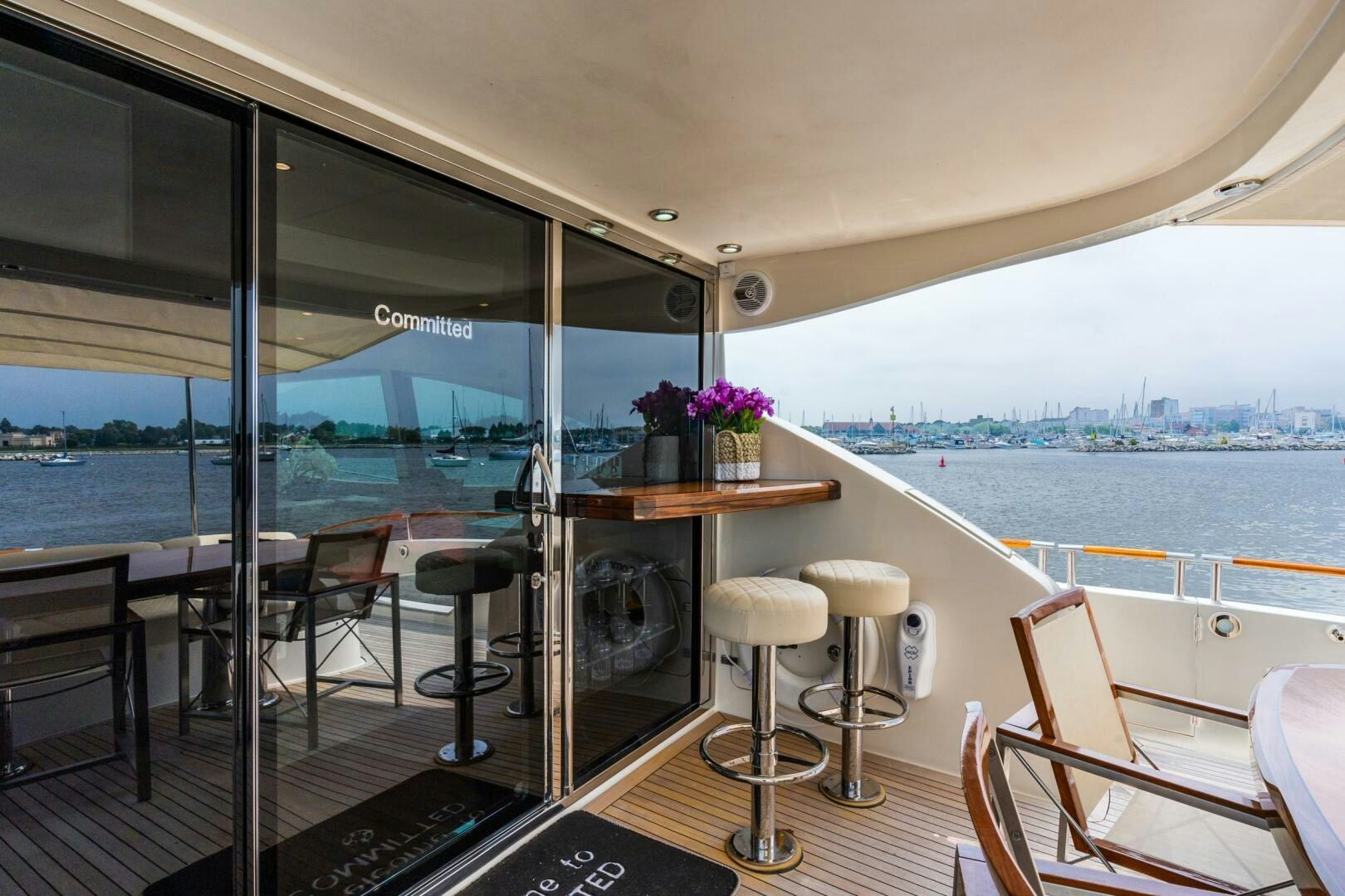 a room with a table and stools and a window with a view of the water aboard COMMITTED Yacht for Sale