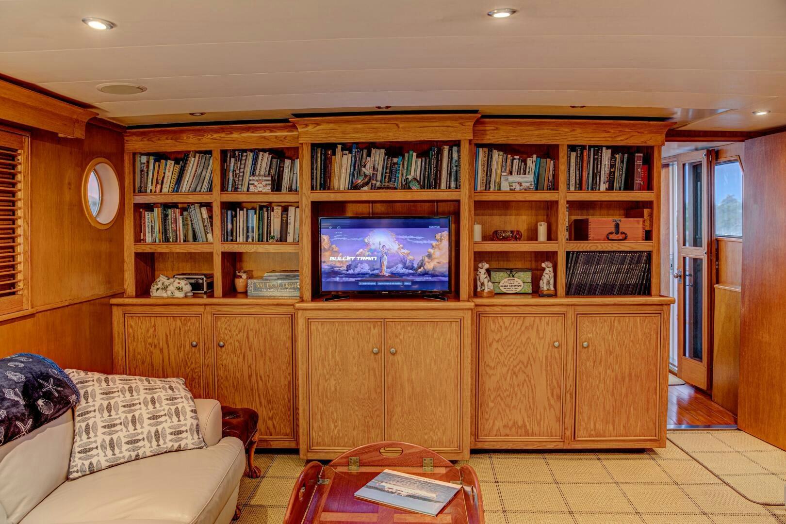 a living room with a tv and a book shelf aboard KOALA Yacht for Sale
