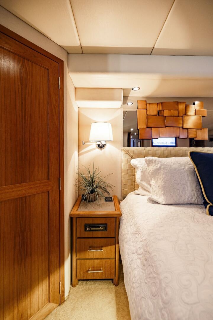 a bedroom with a bed and a wood cabinet aboard LADY LETICIA V Yacht for Sale