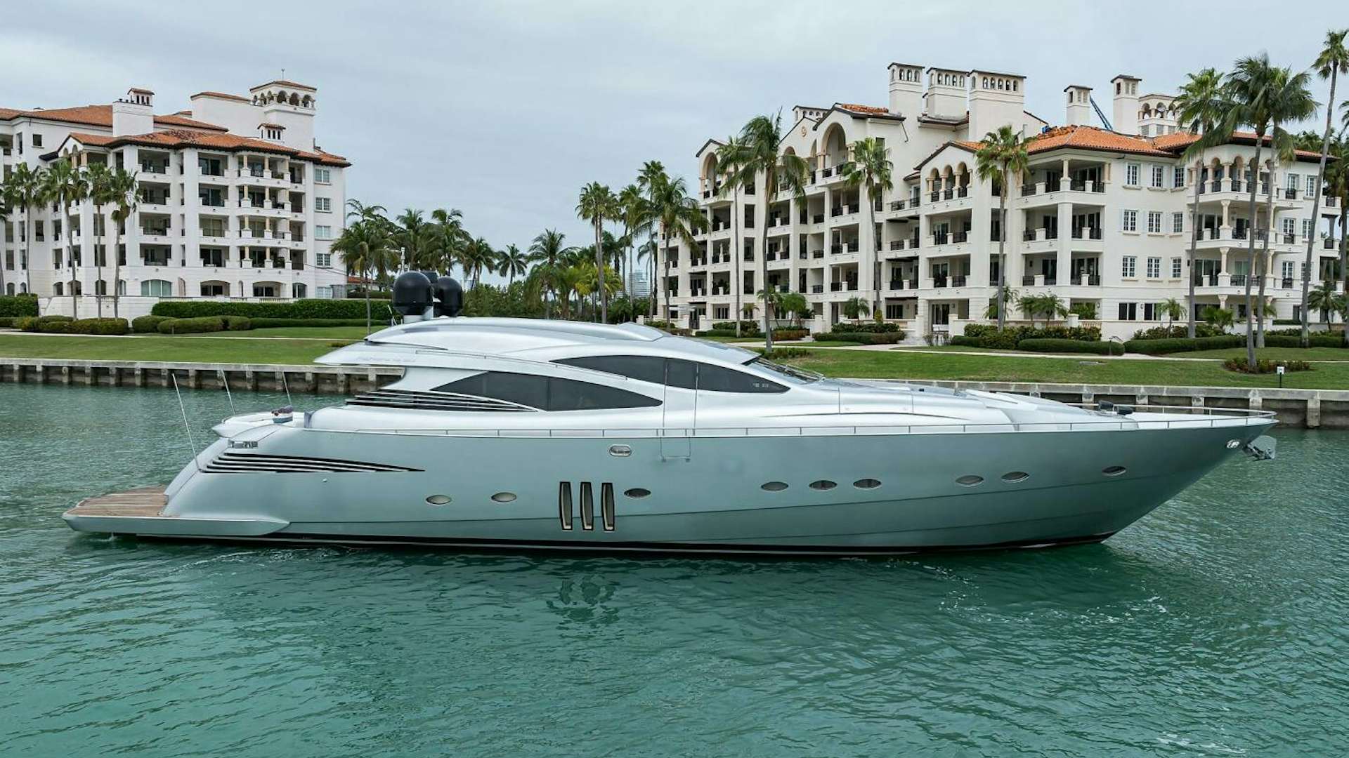 a white boat in a body of water with buildings in the background aboard MIURA Yacht for Sale