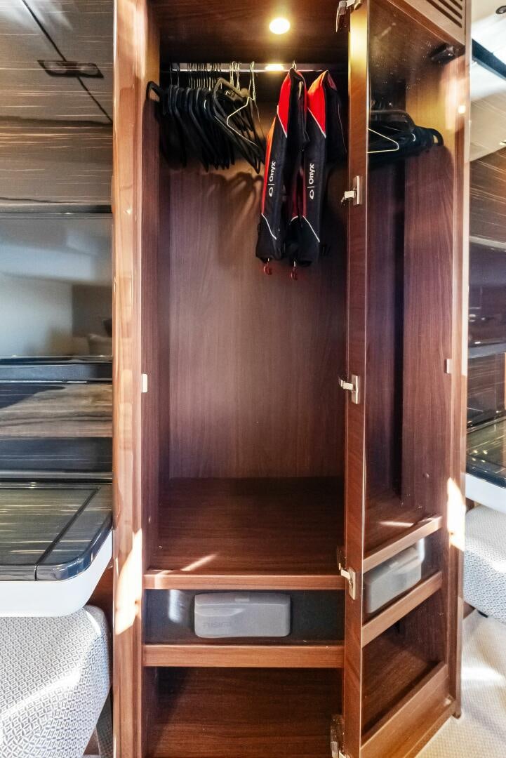 a closet with clothes on the wall aboard AMICI Yacht for Sale