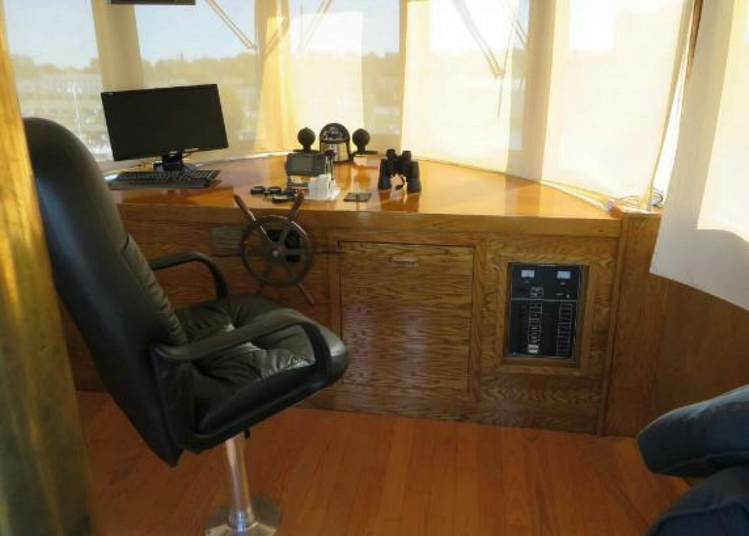 a black office chair next to a computer on a wooden desk aboard PRESCOTONT Yacht for Sale